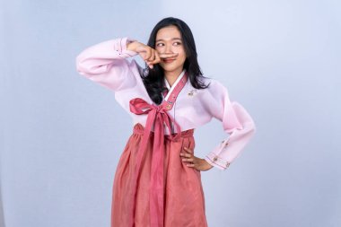 Pembe bir hanbok içinde burnunu işaret parmağıyla kapatan genç bir kadın..