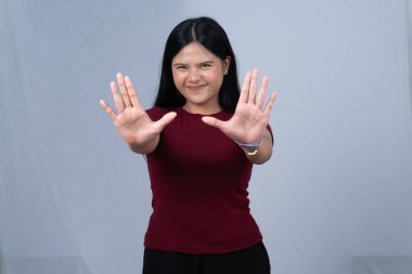 Kestane rengi tişörtlü gülümseyen bir kadın dur ya da dur işareti yapar.