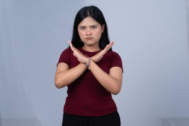 Kestane rengi tişörtlü genç bir kadın kameraya doğru bir jest yapıyor.