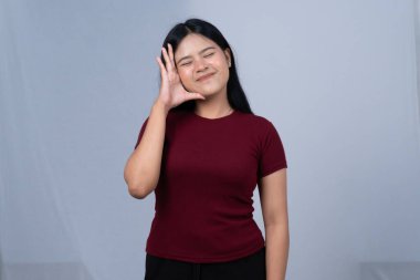 Kestane rengi gömlekli genç bir kadın kulağını kavrayıp gülümsüyor, dikkatle dinliyor.