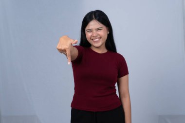 Kestane rengi tişörtlü gülümseyen bir kadın parmağını kameraya doğru tutar.