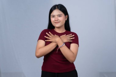 Kestane renkli tişörtlü gülümseyen bir kadın kollarını göğsüne kavuşturmuş duruyor.