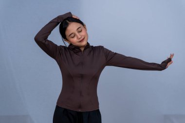 Kahverengi atletik bluzlu bir kadın boynunu uzatıyor.