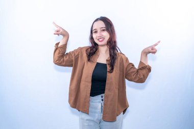 Kahverengi gömlekli mutlu bir Asyalı kadın beyaz bir arka planda sağı solu işaret ediyor.