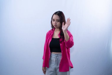 Pembe tişörtlü ciddi bir Asyalı kadın somurtkan bir ifadeyle durur ya da veda eder.