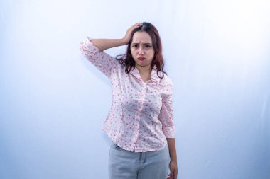 Pembe çiçekli gömlekli stresli bir Asyalı kadın hayal kırıklığı ya da acı içinde başını tutuyor.