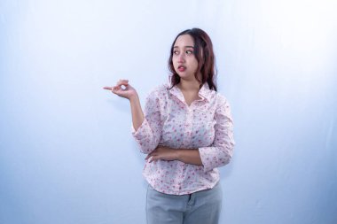 Çiçekli gömlekli Asyalı bir kadın tarafsız ya da biraz şaşırmış bir ifadeyle yanlamasına bakıyor.