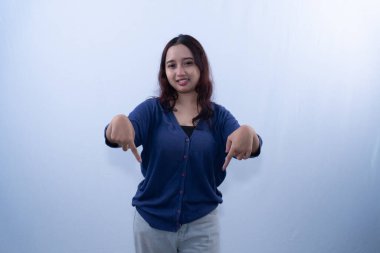 Mavi bluzlu ve gri pantolonlu gülümseyen genç bir kadın iki eliyle aşağıya bakıyor.