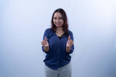 Mavi hırkalı mutlu genç bir kadın küçük kalp hareketleri yaparken gülümsüyor.