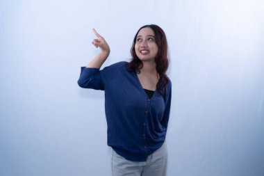 Mavi hırkalı, gülümseyen genç bir kadın şaşırmış bir ifadeyle yukarı bakıyor.