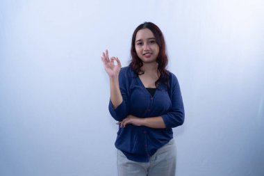 Mavi hırkalı ve gri pantolonlu gülümseyen genç bir kadın, 