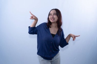 Mavi hırkalı, gülümseyen genç bir kadın beyaz arka planda iki farklı yönü işaret ediyor.