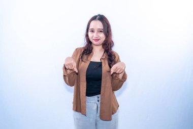 Kahverengi gömlekli, gülümseyen genç bir kadın iki eliyle aşağıya bakıyor.