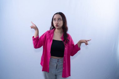 Pembe tişörtlü genç bir kadın, kafası karışmış bir ifadeyle iki yönü işaret ediyor.