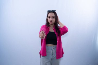 Pembe tişörtlü genç bir kadın kameraya şaşkın bir ifadeyle bakıyor.