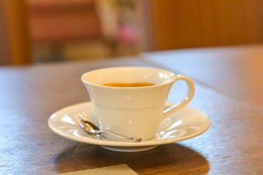 Sıcak americano beyaz bir fincanda ahşap bir masada, bir kahve dükkanında sıcak bir ışıkta..