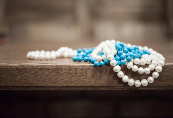 pearls and turquoise beads hang from the edge of the table