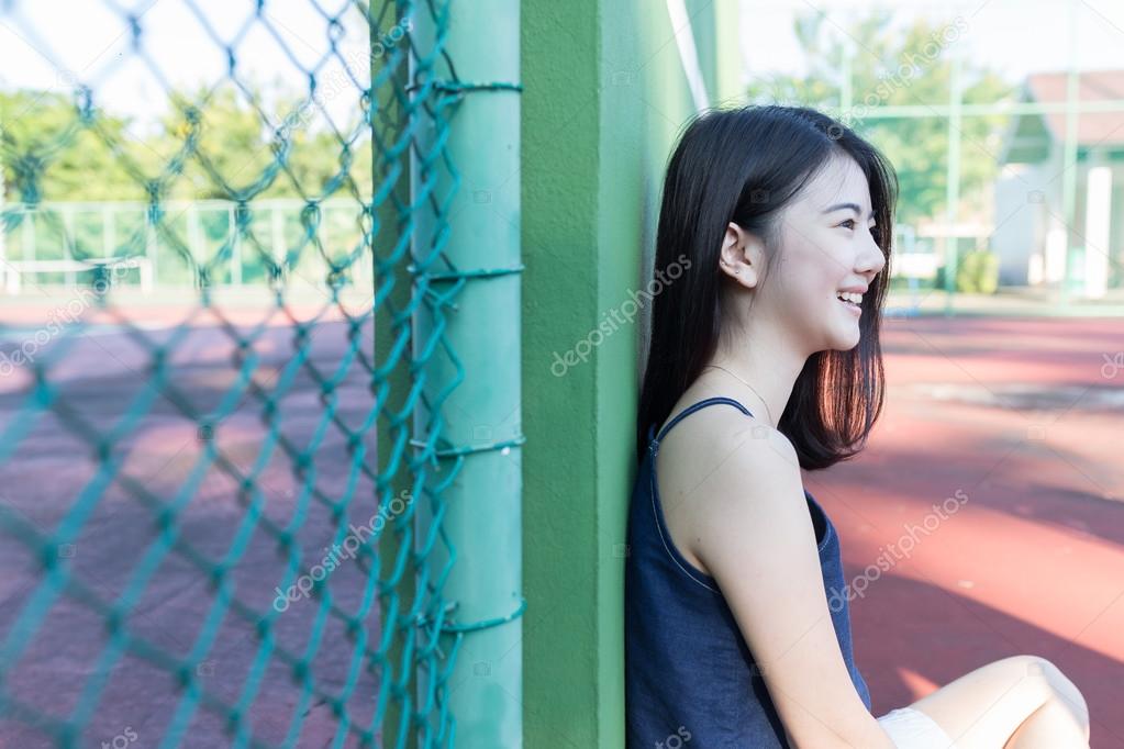 beautiful asian girl on tennis court after playing tennis