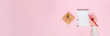 Tatil afişleri, dilek listeleri, yeni yıl planlama, pazarlama planları ve şenlikli tasarım projeleri için geniş bir kopya alanı olan pastel pembe arka planda paketlenmiş hediye kutusunun yanına el yazısı.