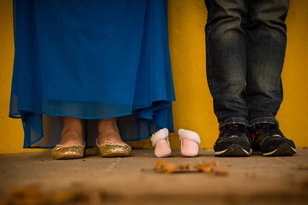 couple's feet and baby shoes