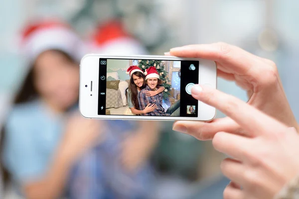 Personas, hombre y mujer tomando fotos, fotos de ellos en el teléfono en el fondo, cerca, árbol de Navidad, fiesta de Navidad, feliz año nuevo 2016 —  Fotos de Stock