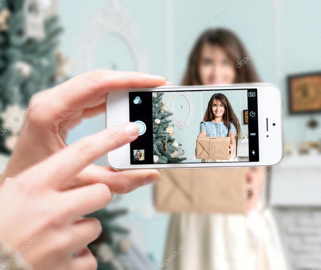 Beautiful girl holding a Christmas gift. Selfie