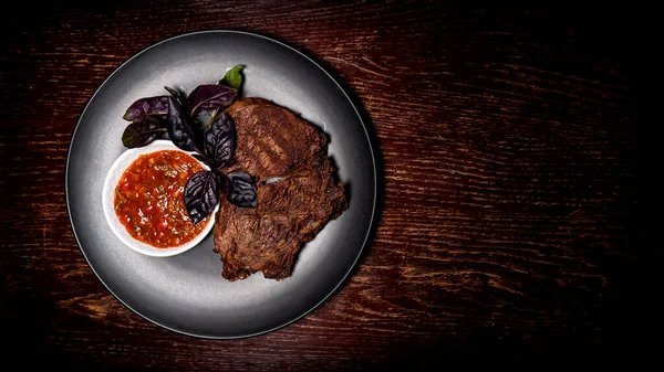 Tabakta kızartılmış et. Restoran yemeği. Soslu ızgara biftek. Ahşap arka plan. T-kemiği.