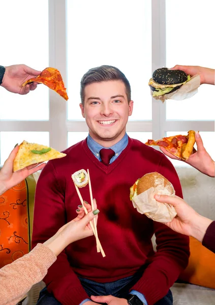 Abur cubur. Çeşitli fast food çeşitleri. Kanepedeki adam. Suşi, pizza ve burgerle bir adamın önünde.
