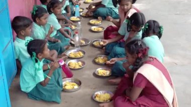 Teşhis edilemeyen, üniformalı, dışarıda oturan, sağ eliyle biraz pirinç yiyen zavallı sınıf arkadaşları. Devlet okulunda öğle yemeği, sağlıksız yemekler.