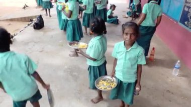 Teşhis edilemeyen, üniformalı, dışarıda oturan, sağ eliyle biraz pirinç yiyen zavallı sınıf arkadaşları. Devlet okulunda öğle yemeği, sağlıksız yemekler.