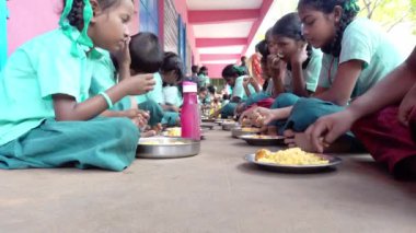 Teşhis edilemeyen, üniformalı, dışarıda oturan, sağ eliyle biraz pirinç yiyen zavallı sınıf arkadaşları. Devlet okulunda öğle yemeği, sağlıksız yemekler.