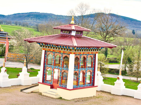 LA BOULAYE, FRANCE - APRIL Circa, 2018. Colorful details of the roof of the one thousand buddhas temple. Wood carving. Multicolored, three-tiered Bhutanese style with statues of Buddhas of various sizes, many Thangka paintings, wall frescoes and frie