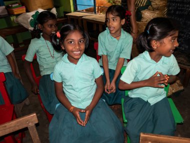 PUDUCHERRY, İNDİA - Aralık 2019. Tanımlanamayan mutlu öğrenciler devlet okulu üniformalı sınıf arkadaşları evde oturup ders çalışıyorlar. Yardım için gülümseyen zavallı çocukların portresi.