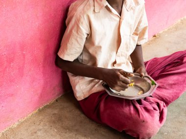 PUDUCHERRY, TAMIL NADU, Hindistan - Aralık 2018. Tanımlanamayan yoksul sınıf arkadaşları üniformalı çocuklar dışarıda oturuyorlar ve sağ elleriyle biraz pirinç yiyorlar. Sağlıksız öğle yemeği