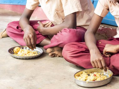 PUDUCHERRY, TAMIL NADU, Hindistan - Aralık 2018. Tanımlanamayan yoksul sınıf arkadaşları üniformalı çocuklar dışarıda oturuyorlar ve sağ elleriyle biraz pirinç yiyorlar. Sağlıksız öğle yemeği