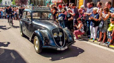 Aziz Michael L 'Eglise, FRANSA - 6 Haziran 2019. Normandiya Çıkarması 'nın kutlanması, silahlı çıkarma, İkinci Dünya Savaşı' nın Normandiya 'da sona ermesi, müttefik ülkelerin yardımıyla. Askerler sokakta izleyicilerle eski peugeot yürüyüşü yapıyor.