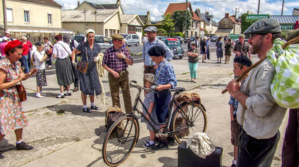 SAINTE MERE L'EGLISE, FRANCE - JUNE 6, 2019. Parade of People dressed up in 1940's clothing posing in front of a World War 2, D-Day ceremony in Normandy. People found liberty after 5 years war. Happy day memorial