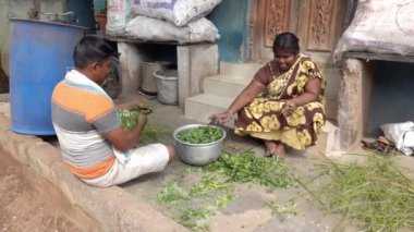 PUDUCHERY-İNDİYA, Aralık 2020. Kimliği belirsiz erkek kadın sokak köyünde sebze hazırlıyor. Evleri küçük, içinde yemek pişirecek fakir insanlarla ilgili gerçek bir Hint sahnesi...