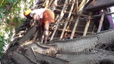 PUDUCHERRY, İNDİA - Aralık 2018. Tanımlanamayan Hintli işçiler turistlere servis yapmak için odunluğun tepesini hindistan cevizi yapraklarıyla kapladılar. Dalit halkı için zor bir iş.