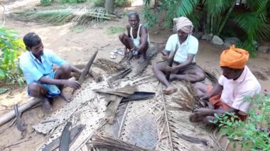 PUDUCHERRY, İNDİA - Aralık 2018. Tanımlanamayan Hintli işçiler turistlere servis yapmak için kütük kulübesinin tepesini hindistan cevizi yapraklarıyla kaplamaya hazırlanıyorlar. Dalit halkı için zor bir iş.