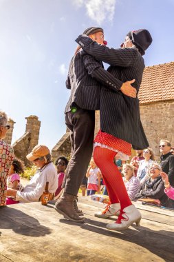 VALOGNES, FRANCE - EPTEMBER Circa, 2020. Tanımlanamayan sokak müzisyenleri ve dansçılar dışarıda şarkı söyleyip dans ediyorlar. Mutlu izleyicilerin olduğu çok komik bir program. Halka açık etkinlikte geleneksel Fransızca müzik.