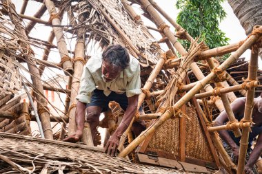 Çapulcu, TAMIL NADU - Aralık 2018. Tanımlanamayan Hintli işçiler turistlere servis yapmak için odunluğun tepesini hindistan cevizi yapraklarıyla kapladılar. Dalit halkı için zor bir iş.