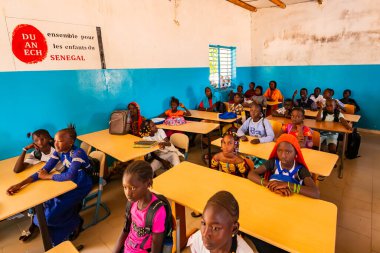 Bour, Senegal - Aralık 2020 civarı. Tanımlanamayan ciddi ve üzgün Afrikalı çocuklar ilkokuldaki bir sınıfta masalarında oturuyorlar. Yeni masaları, çatısı, tabloları olan yeni sınıf. Uluslararası STK yardımları nedeniyle.