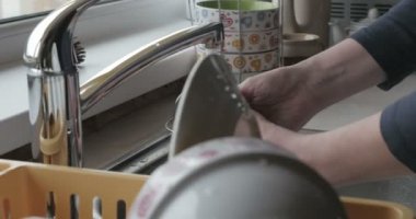 Kadın lavaboda bulaşık yıkıyor.