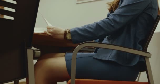 Nő ül az asztalnál, megy keresztül papírok, az asztalon az irodában — Stock videók