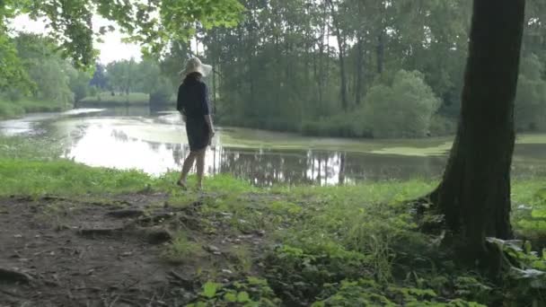 Una mujer con un sombrero en el lago en el Parque — Vídeo de stock