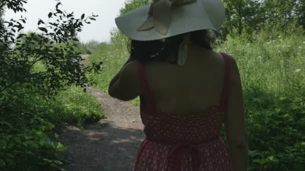 Young girl in hat and long dress comes along the path, fps96 — Stock Video