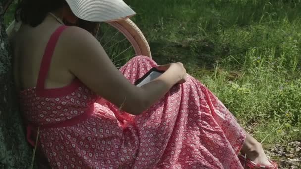 Young woman in Park reading e-book — Stock Video