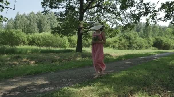 Девушка в парке держит букет цветов и улыбается — стоковое видео