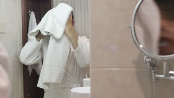 Młody człowiek w szlafrok suszarka do jego włosów w łazience — Wideo stockowe